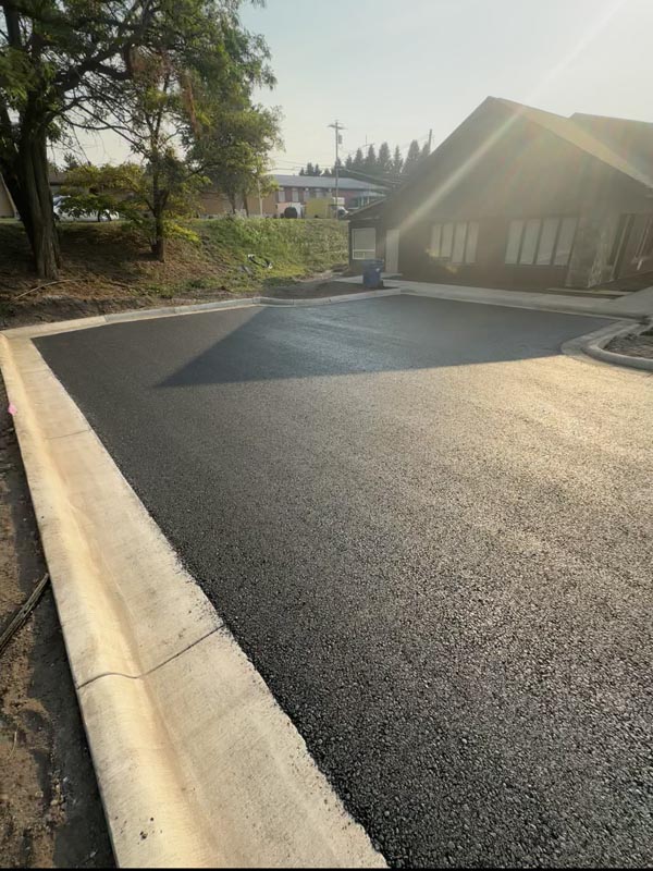 Fresh asphalt parking area formed around concrete curbs